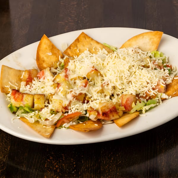 Toro Loco's Mexican salad with chicken, lettuce, tomatoes, cheese, and tortilla chips on a white plate.